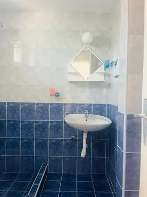 a blue tiled bathroom with a sink and a mirror at Apartments MM Budva in Budva