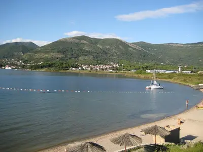 a boat in the water on a beach with mountains at Green Harmony in Tivat