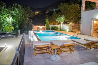 a swimming pool with tables and chairs next to a house at Villa Del Mar in Sutomore