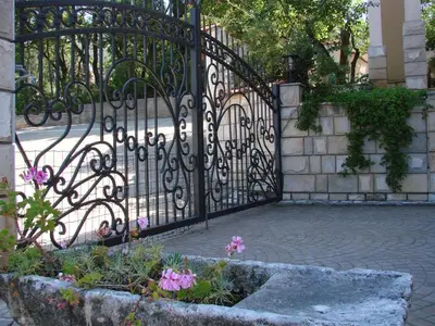 a black iron gate with flowers in a garden at Villa Del Mar in Sutomore