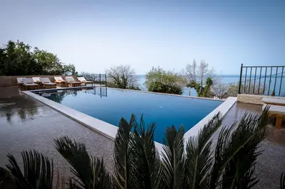 a swimming pool with chairs and the ocean in the background at Villa Del Mar in Sutomore