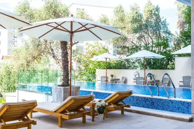 a swimming pool with two chairs and an umbrella at B&B Amfora in Petrovac na Moru