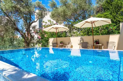 a swimming pool with two umbrellas and a swimming pool at B&B Amfora in Petrovac na Moru