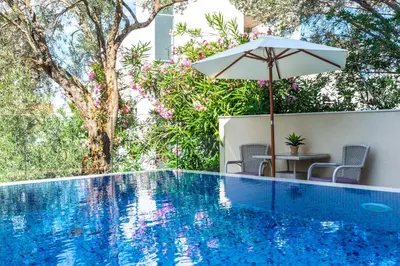 a pool with an umbrella and chairs and a table with an umbrella at B&B Amfora in Petrovac na Moru