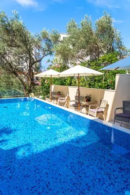 a swimming pool with chairs and umbrellas on a building at B&B Amfora in Petrovac na Moru