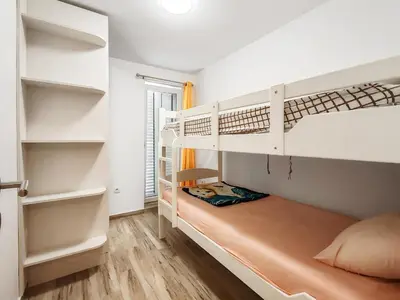 a bedroom with white bunk beds and wooden floors at Villa Masha in Rijeka Reževići