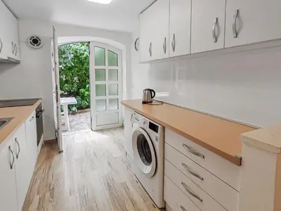 a kitchen with white cabinets and a washer and dryer at Villa Masha in Rijeka Reževići