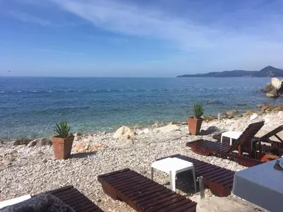 a group of chairs and tables on a rocky beach at Villa Masha in Rijeka Reževići