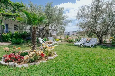 a yard with chairs and a palm tree and flowers at Sea Garden Apartments in Dobra Voda