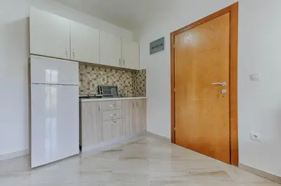 a kitchen with white cabinets and a wooden door at Sea Garden Apartments in Dobra Voda