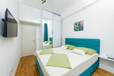 a bedroom with a large bed with a blue headboard at Lux Apartments Harmonia in Budva