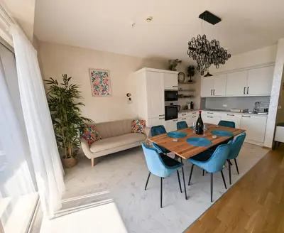 a kitchen and living room with a wooden table and blue chairs at Lux Apartments Harmonia in Budva