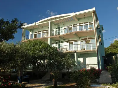 a large white building with balconies and trees at Arabela Apartments in Utjeha