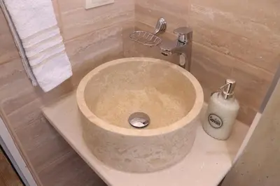 a stone sink in a bathroom with a shower at Gjinaj Apartments in Ulcinj