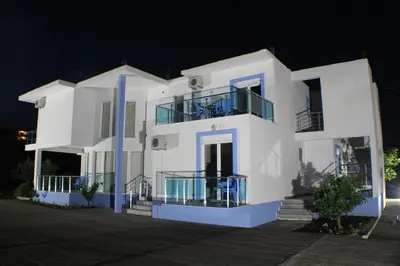 a white house with blue balconies at night at Gjinaj Apartments in Ulcinj