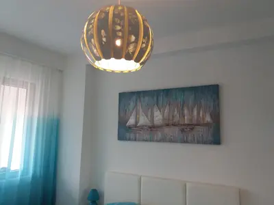 a chandelier in a room with a painting of sailboats at Apolonia Lux Apartment in Budva
