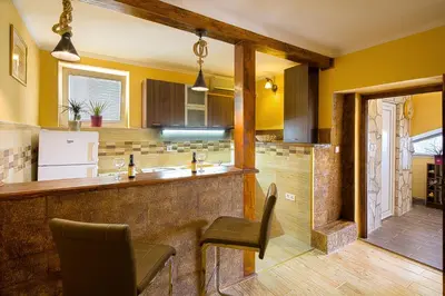 a kitchen with yellow walls and a counter and chairs at Apartman Kunjić in Krimovice