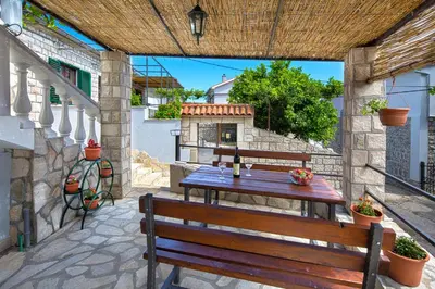 a table and bench on a patio with a fireplace at Apartman Kunjić in Krimovice
