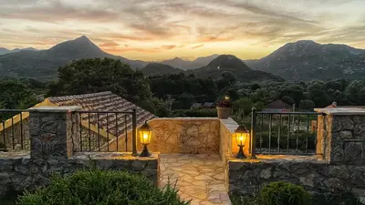 a stone house with two lights on it with mountains in the background at Eco Villas Merak in Virpazar