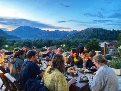 a group of people sitting at a table eating food at Eco Villas Merak in Virpazar
