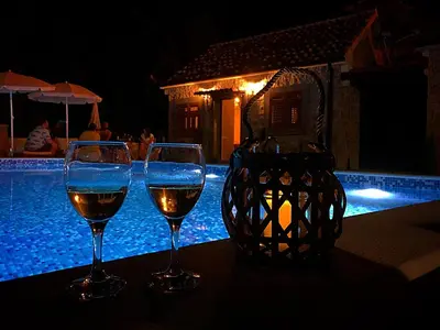 two glasses of wine sitting on a table next to a pool at Eco Villas Merak in Virpazar