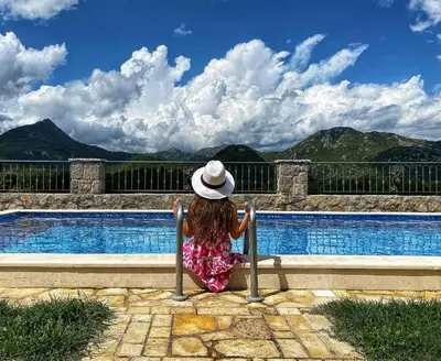 a little girl sitting on a bench next to a swimming pool at Eco Villas Merak in Virpazar
