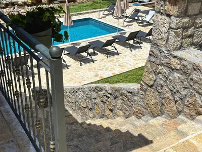 a fence next to a swimming pool with chairs at Eco Villas Merak in Virpazar