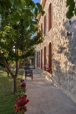 a stone building with a bench next to a tree at Apart & Spa Beganovic in Dobra Voda