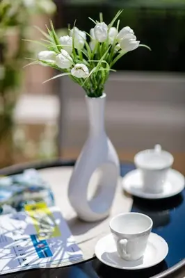 a white vase with white flowers on a table at Passage Apartments in Kotor