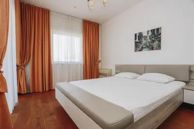 a bedroom with a large white bed with orange curtains at Apartment Mimosa of Tre Canne in Budva