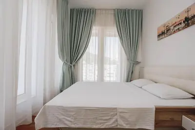 a bedroom with a bed with green curtains and a window at Apartment Mimosa of Tre Canne in Budva