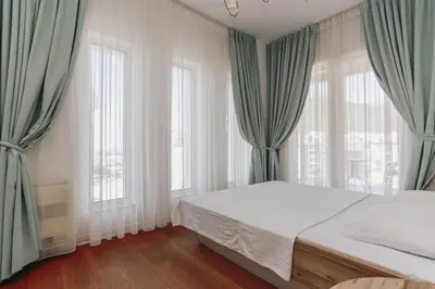 a bedroom with green curtains and a bed with white sheets at Apartment Mimosa of Tre Canne in Budva