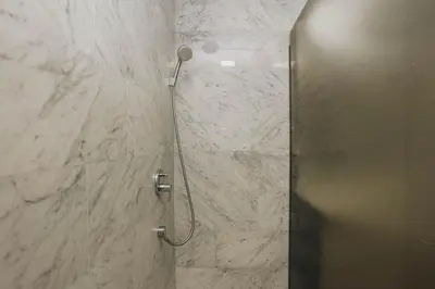 a shower in a bathroom with a marble wall at Apartment Mimosa of Tre Canne in Budva