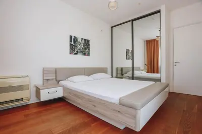 a white bedroom with a bed and a television at Apartment Mimosa of Tre Canne in Budva