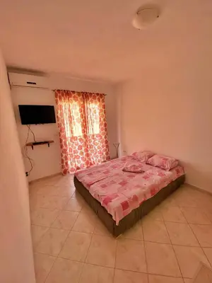 a bedroom with a bed with a pink comforter at Rajovic Apartments in Tivat