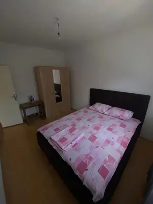 a bedroom with a bed with a pink comforter at Rajovic Apartments in Tivat