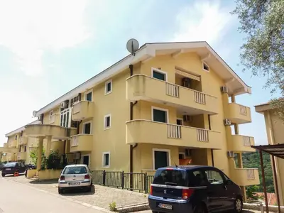 two cars parked in front of a yellow building at Allegro Apartment Sekulic in Petrovac na Moru