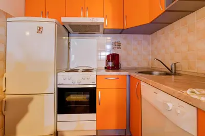 a kitchen with orange cabinets and a white refrigerator at Allegro Apartment Sekulic in Petrovac na Moru