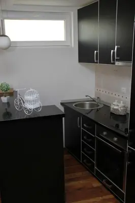 a kitchen with black cabinets and a sink and a window at Ruza apartman in Budva