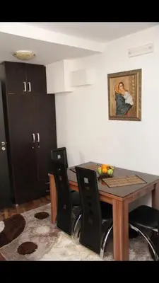 a dining room table with black chairs and a painting on the wall at Ruza apartman in Budva