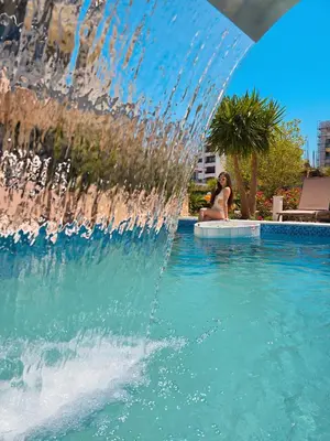 a woman sitting next to a fountain in a pool at Miami apartments in Ulcinj
