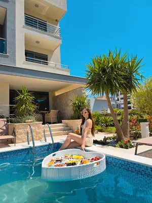 a woman sitting in a pool next to a swimming pool at Miami apartments in Ulcinj