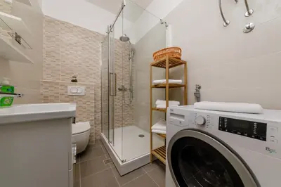 a washing machine in a bathroom with a shower at Old Town Clock Tower Apartment in Kotor