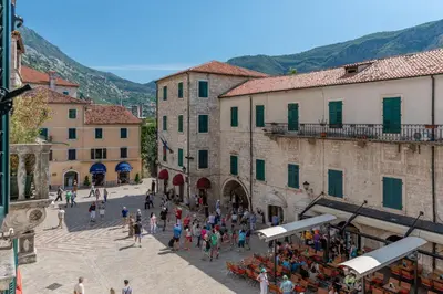 a group of people walking around a town with buildings at Old Town Clock Tower Apartment in Kotor