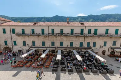 a group of people sitting in chairs in front of a building at Old Town Clock Tower Apartment in Kotor