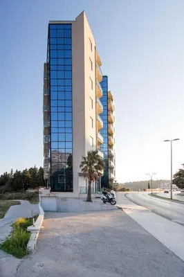 a tall building with a palm tree in front of it at Bečiči -Big apartments in Becici