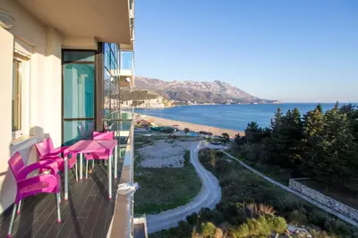 a balcony with pink chairs and a view of a beach at Bečiči -Big apartments in Becici