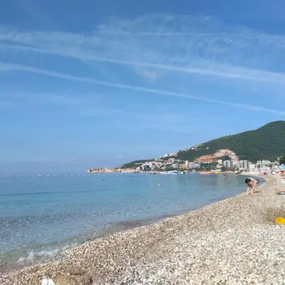 a person is standing on a rocky beach at Sunčani apartman 2-Vila Amfora in Budva