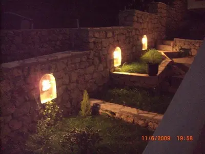 a stone wall with lights in a yard at night at Villa Beba in Dobra Voda