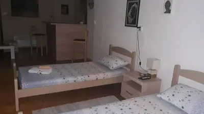 a room with two beds and a table and a room with at Apartman Centar in Cetinje